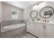 Elegant bathroom featuring double sinks, round mirrors, modern lighting, and a luxurious soaking tub at 102 Linda Ln, Lake Mary, FL 32746