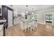 Bright kitchen features an island with white stools, modern lighting, and sliding glass doors to the backyard at 102 Linda Ln, Lake Mary, FL 32746