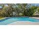 A swimming pool with fountains built into the tile and a wide concrete border, surrounded by mature trees at 102 Linda Ln, Lake Mary, FL 32746