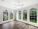 Bright living room with hardwood floors, a ceiling fan, and four large windows at 109 Greentree Ln, Yalaha, FL 34797