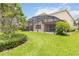 Expansive backyard with lush green grass, mature landscaping, and a screened-in patio, perfect for outdoor living at 12286 Regal Lily Ln, Orlando, FL 32827