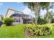 Gorgeous landscaped backyard featuring manicured green lawn, mature palm trees, and a screened patio area at 12286 Regal Lily Ln, Orlando, FL 32827