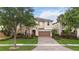 Attractive two-story home with a well-maintained lawn, brick driveway, and lush tropical landscaping at 12286 Regal Lily Ln, Orlando, FL 32827