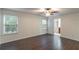 This spacious bedroom features wood-look flooring, a ceiling fan, and bright, natural light from two windows at 1356 Scarlet Oak Loop, Winter Garden, FL 34787