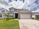 Charming two-story home features a brick driveway, manicured lawn, and welcoming covered porch at 13617 Haulover Beach Ln, Orlando, FL 32827