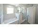 Bright bathroom featuring a tub with marble tile surround and glass-enclosed shower at 14308 Abington Heights Dr, Orlando, FL 32828