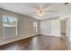 Neutral bedroom featuring wood-look floors, two large windows, a ceiling fan, and a white door leading to another room at 1821 Geigel Ave, Orlando, FL 32806