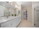 Bright bathroom featuring double sinks, a walk-in shower, and a spacious walk-in closet for organized storage at 1962 Flora Pass Pl, Kissimmee, FL 34747