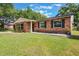 Well-maintained single-story red brick home with lush green lawn and simple landscaping at 209 Carriage Hill Dr, Casselberry, FL 32707