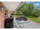 Covered outdoor patio area with comfortable wicker furniture, a grill, and a view of the spacious, fenced backyard at 209 Carriage Hill Dr, Casselberry, FL 32707