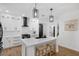 Open-concept kitchen boasts white cabinets, island with bar seating, and modern black accents at 215 Foxglove Way, Deland, FL 32724