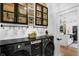 Modern laundry room featuring black countertops, white shiplap walls, and custom storage cabinets at 215 Foxglove Way, Deland, FL 32724