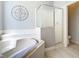 Bright bathroom features a soaking tub, tiled walls, and a walk-in shower with glass door at 2705 Grand Harbour Ct, Kissimmee, FL 34747