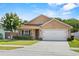 Single-story home featuring a lush front lawn, flowering tree, and attached two-car garage at 2980 Cool Breeze Cir, St Cloud, FL 34769