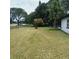 Large, partially mowed back yard featuring mature trees and a screened in porch along the side of the house at 3 Spur Ct, Kissimmee, FL 34743