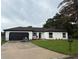 Charming single-story home with a well-maintained lawn, freshly painted, and a black garage door at 3 Spur Ct, Kissimmee, FL 34743