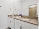 Bright bathroom with double sinks, quartz counters, white cabinets, and tiled shower at 4185 Paragraph Dr, Kissimmee, FL 34746