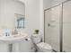 Bright bathroom featuring a pedestal sink, toilet, and glass-enclosed shower at 4185 Paragraph Dr, Kissimmee, FL 34746