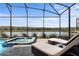 Relaxing pool area with a spa and lounge chairs under a screened enclosure with lake views at 4185 Paragraph Dr, Kissimmee, FL 34746