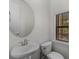 The half bath features a round mirror, pedestal sink and a window to let in natural light at 4562 Lower Park Rd, Orlando, FL 32814
