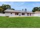 View of the spacious backyard with a green lawn, patio, and the house's exterior with a chimney at 5130 Sun Palm Dr, Windermere, FL 34786