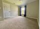 Neutral carpeted bedroom featuring a window with drapes and a white door at 660 Neile Ct, Oviedo, FL 32765