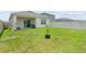 Lush backyard featuring a green lawn, white fence, and covered patio, providing a serene outdoor living area at 7112 Mottled Duck Dr, Harmony, FL 34773