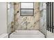 Close up of the marble tiled shower featuring gold trim, a rain shower head and a black heated towel rack at 7733 Pointe Venezia Dr, Orlando, FL 32836