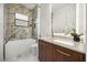 Modern bathroom features a marble-clad shower/tub and a wood vanity with marble countertop at 7733 Pointe Venezia Dr, Orlando, FL 32836