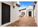 Outdoor courtyard with brick pavers and white stucco walls, featuring a seating area and arched entryway at 7733 Pointe Venezia Dr, Orlando, FL 32836