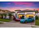 Mediterranean-style home at sunset with two-car garage, lush landscape, and decorative gate; sports cars parked in driveway at 7733 Pointe Venezia Dr, Orlando, FL 32836