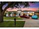 Stunning home at dusk boasts lush lawn, tile roof, and multiple luxury cars in the driveway and garage at 7733 Pointe Venezia Dr, Orlando, FL 32836