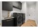Modern laundry room with sleek black cabinets, gold fixtures, marble countertops, and high-end appliances at 7733 Pointe Venezia Dr, Orlando, FL 32836