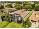 Aerial view of screened pool and patio in backyard of home with red-tiled roof in a residential area with mature trees at 7733 Pointe Venezia Dr, Orlando, FL 32836