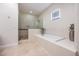 Bright bathroom featuring a glass-enclosed shower, soaking tub, and neutral tile floors at 800 Hamilton Place Ct, Winter Park, FL 32789