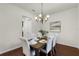 Inviting dining area with a rustic table, cushioned chairs, a modern chandelier, and an elegant piece of artwork at 8113 Key West Dove St, Winter Garden, FL 34787