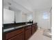 Stylish bathroom featuring dark granite countertops, wood cabinets, and a large mirror above the sink, exuding elegance at 9115 Longship Aly, Orlando, FL 32832