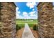 Beautiful community entrance framed by stone columns with a view of the scenic pond at 9115 Longship Aly, Orlando, FL 32832