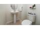 Compact half bathroom featuring a pedestal sink, toilet, decorative accents, and neutral wall colors at 9115 Longship Aly, Orlando, FL 32832