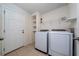 Functional laundry room with a door to the outside, washer, dryer, storage shelves, and tiled flooring at 9115 Longship Aly, Orlando, FL 32832