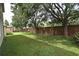 Spacious backyard with brick wall, green grass and mature trees providing shade at 9223 Leeland Archer Blvd, Orlando, FL 32836
