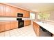 Light and airy kitchen featuring wooden cabinets, black appliances, tile floors, and plenty of natural light at 9223 Leeland Archer Blvd, Orlando, FL 32836