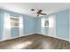 Bedroom with light blue walls, wood-look flooring, two windows, and white curtains at 1008 Bay Ave, Lake Wales, FL 33859