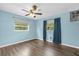 Bedroom with blue walls, wood-look flooring, ceiling fan, and windows with shades at 1008 Bay Ave, Lake Wales, FL 33859