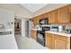 Efficient kitchen with light wood cabinets, white countertops, stainless steel refrigerator, and black appliances, located near the dining area at 1039 Eagles Forrest Dr, Apopka, FL 32712