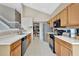 Spacious kitchen with light wood cabinets, modern black appliances, and white countertops, adjacent to the dining room and stairs at 1039 Eagles Forrest Dr, Apopka, FL 32712