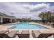 Resort-style community pool with surrounding lounge chairs, umbrellas, and manicured landscaping at 12821 Harvest Rain Ave, Winter Garden, FL 34787