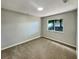 Well-lit bedroom featuring a round skylight, a window with a view of foliage, and gray carpet at 13108 Long Pine Trl, Clermont, FL 34711