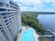 High-rise building with a large pool next to a lush green area near a lake at 13427 Blue Heron Dr # 2-1401, Orlando, FL 32821