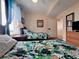 Bedroom with two beds featuring bright tropical patterned bedding, a window, and a dresser with a TV at 13427 Blue Heron Dr # 2-1401, Orlando, FL 32821